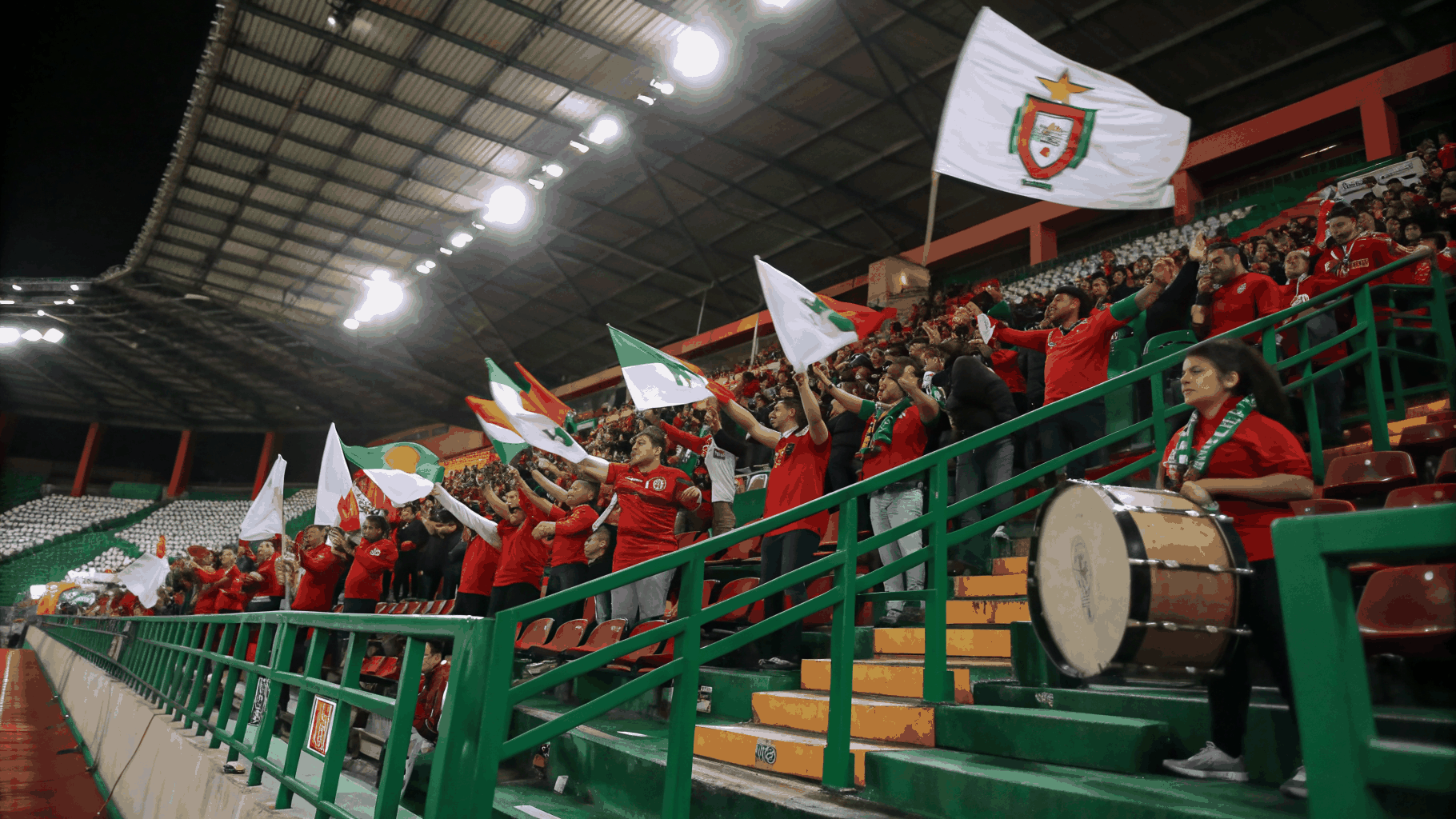 Stadyum tribünlerinde renkli meşaleler, bayraklar ve taraftarların canlı coşkulu koreografisi